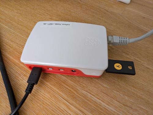 A Raspberry Pi in a plastic enclosure, with power and Ethernet feeding in and a YubiKey sticking out
